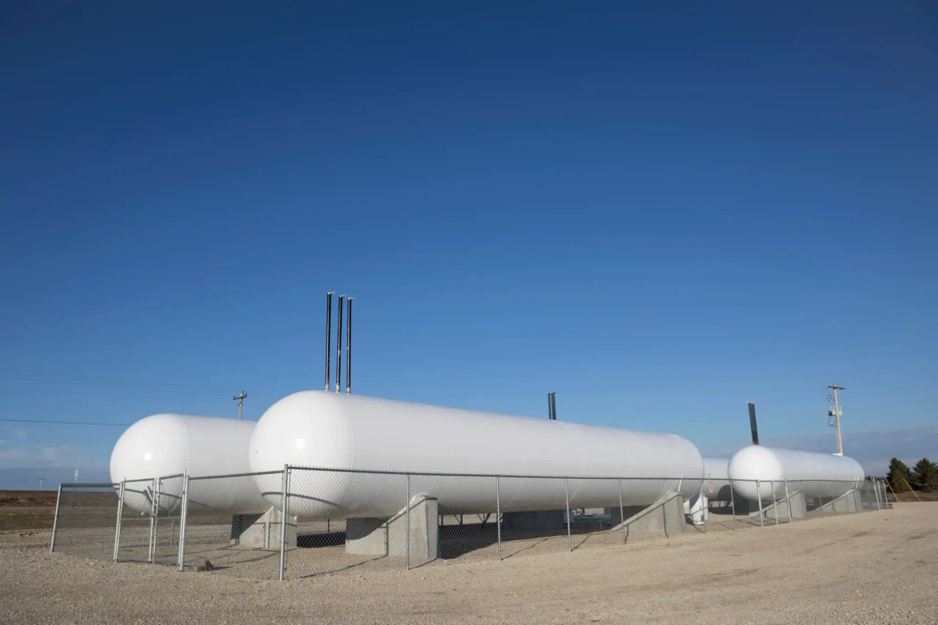 Large white industrial storage tanks under a clear blue sky.