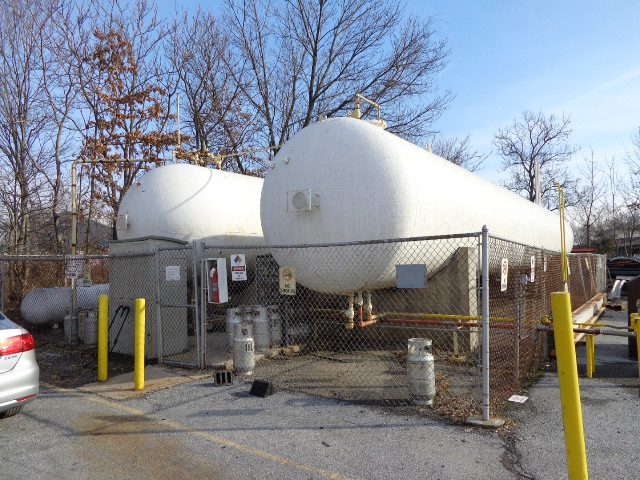 Two large white propane tanks at an outdoor storage facility.