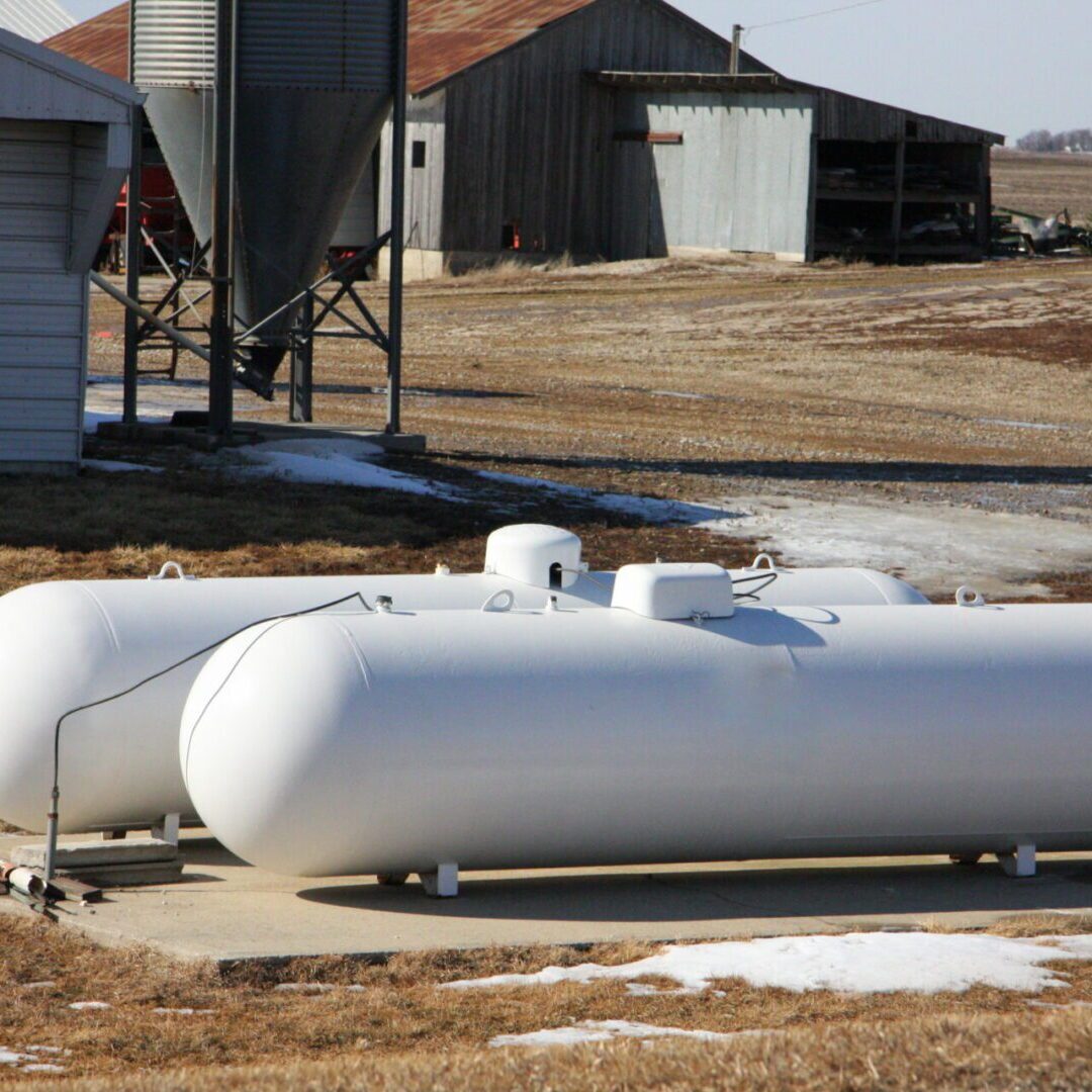 Large white propane tanks outdoors near storage buildings.