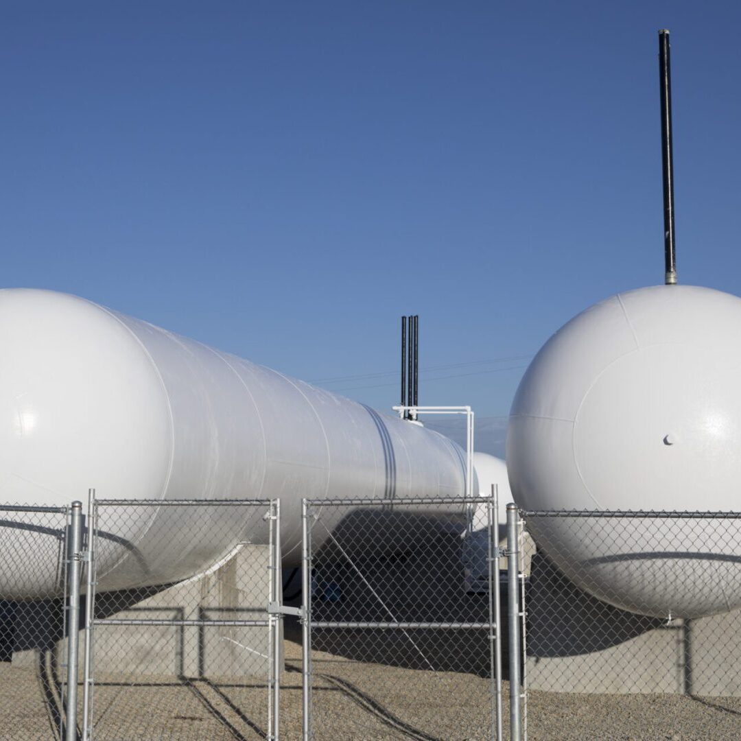 Two large white industrial storage tanks under a clear blue sky.
